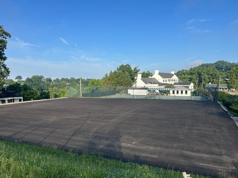 Fresh asphalt lot overlooking a white historic building and green hills
